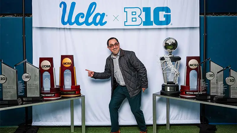 A man posing for a picture with a 'UCLA x B1G' banner behind them