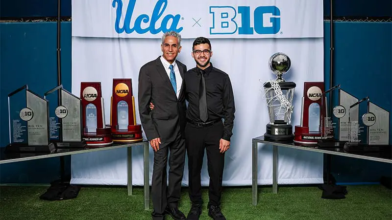 Two men posing for a picture with a 'UCLA x B1G' banner behind them